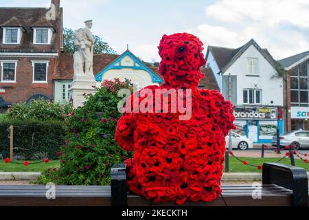 Chesham, Buckinghamshire. VEREINIGTES KÖNIGREICH. 11. November 2022. Eine auffällige Figur zum Gedenktag, in der ein Mann mit roten Mohnblumen auf einem Sitz in Chensham neben dem Kriegsdenkmal sitzt und eine weiße Taube in der Hand hält. Quelle: Maureen McLean/Alamy Live News Stockfoto