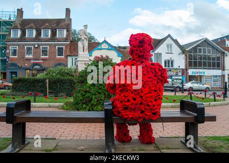 Chesham, Buckinghamshire. VEREINIGTES KÖNIGREICH. 11. November 2022. Eine auffällige Figur zum Gedenktag, in der ein Mann mit roten Mohnblumen auf einem Sitz in Chensham neben dem Kriegsdenkmal sitzt und eine weiße Taube in der Hand hält. Quelle: Maureen McLean/Alamy Live News Stockfoto