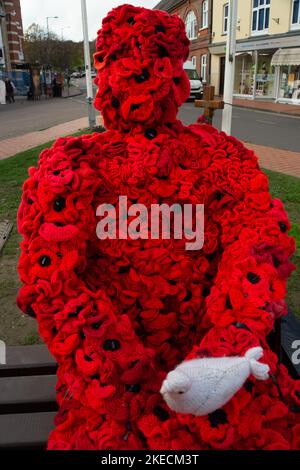 Chesham, Buckinghamshire. VEREINIGTES KÖNIGREICH. 11. November 2022. Eine auffällige Figur zum Gedenktag, in der ein Mann mit roten Mohnblumen auf einem Sitz in Chensham neben dem Kriegsdenkmal sitzt und eine weiße Taube in der Hand hält. Quelle: Maureen McLean/Alamy Live News Stockfoto