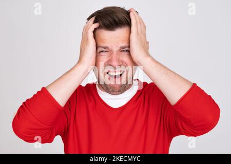 Ein besorgter Weißer, der Kopf in den Händen hält, sieht besorgt aus. Stockfoto