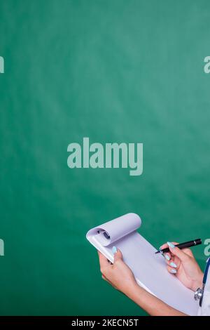 Doktor, der medizinischen Bericht für ihren Patienten füllt.Doktor mit Stethoskop in weißem Mantel, der Zwischenablage hält, medizinische Aufzeichnung Diagnose schreibt, isoliert auf Stockfoto