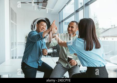 Lächelnde Gruppe multiethnischer Kollegen, die während der Pause Kaffee trinken und sich unterhalten Stockfoto