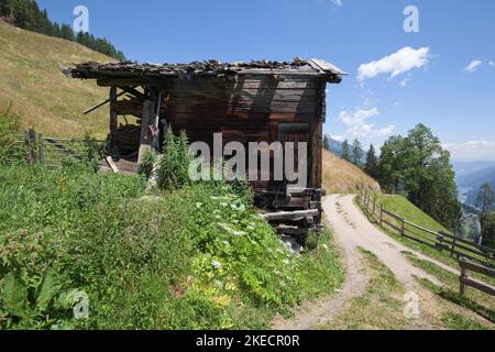 Alte verfallene Holzhütte steht auf der Schotterstraße im steilen Hang, dem Südtiroler Ultental Stockfoto