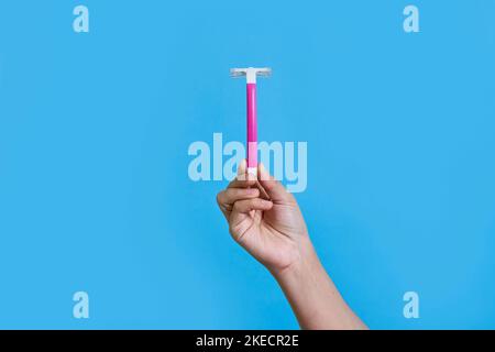 Die Hand einer Person hält eine rosa Zahnbürste auf einem blauen Hintergrund und in der rechten oberen Ecke befindet sich ein Kopierplatz Stockfoto
