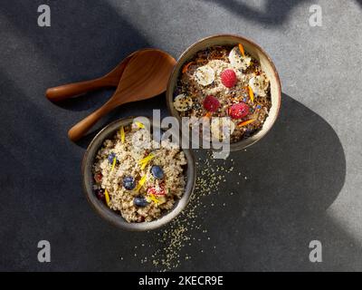 ayurvedische Küche, zwei Tonschüsseln mit Grießbrei und Früchten auf einem dunklen Steinteller Stockfoto