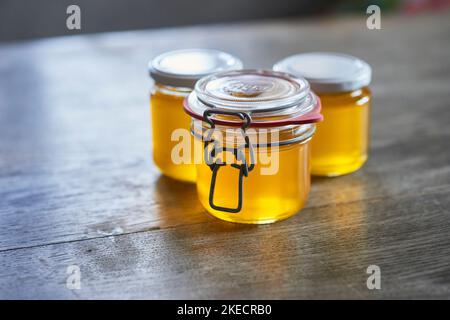 ayurvedische Ernährung, Schritte zur Zubereitung von hausgemachtem Ghee aus Butter - gefilterter, noch flüssiger Ghee in drei Vorratsgläsern. Stockfoto