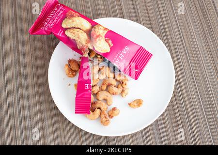 Tambov, Russische Föderation - 06. Oktober 2018 eine offene Packung Sahale Snacks, Glazed Mix, Granatapfel-Vanille aromatisierte Cashewkerne auf einem weißen Teller. Bambus Stockfoto