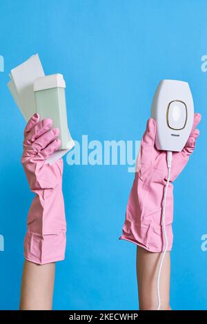 Zwei Hände in rosa Handschuhen, die oben und unten eine weiße Schachtel mit einem elektronischen Gerät halten Stockfoto