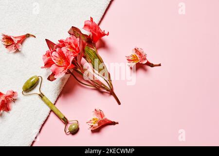 Einige rosa Blüten auf einem weißen Handtuch neben einer Schere und einem Stück Papier, das in zwei Hälften geschnitten wurde Stockfoto