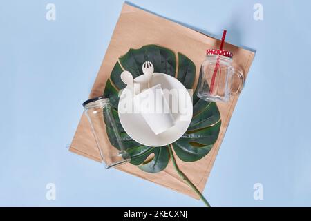 Ein Tischset mit Tellern, uts und Servietten auf dem Tischset vor blauem Hintergrund Stockfoto