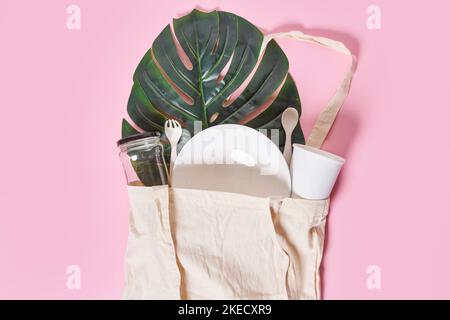 Ein mit Lebensmitteln und uts gefüllter Beutel auf einem rosa Hintergrund daneben ist ein grünes Blatt Stockfoto