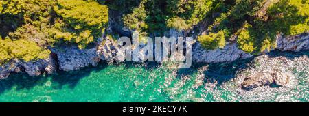 BANNER, LANGFORMATIGES malerisches Meer Adriaküste von Montenegro. Türkisfarbenes Mittelmeer und felsige Küste mit immergrünen Nadelbäumen. Wunderbar Stockfoto