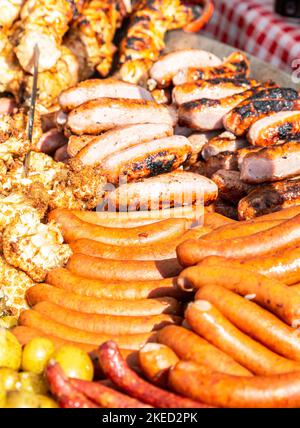 Leckere Würstchen vom Fleischbraten über heißen Kohlen für ein Picknick-Mittagessen Stockfoto