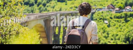 BANNER, LANGFORMAT MONTENEGRO. Mann Tourist im Hintergrund der Dschurdschewitsch-Brücke über den Fluss Tara. Reisen Sie durch Montenegro Konzept. Sehenswürdigkeiten von Stockfoto