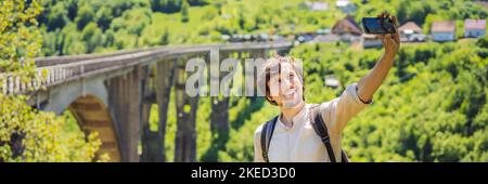 BANNER, LANGFORMAT MONTENEGRO. Mann Tourist im Hintergrund der Dschurdschewitsch-Brücke über den Fluss Tara. Reisen Sie durch Montenegro Konzept. Sehenswürdigkeiten von Stockfoto