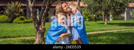 BANNER, LANG FORMAT ukrainische Mutter mit zwei Kindern mit Flagge der Ukraine. Draußen. Konzept des Problems des Krieges in Europa, Unterstützung von Familien und Stockfoto