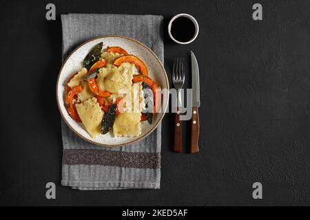 Hausgemachter Kürbis Ravioli mit Ricotta-Käse serviert Salbei Butter und Hartkäse auf Teller auf dunklem Tisch. Draufsicht, Kopierraum Stockfoto