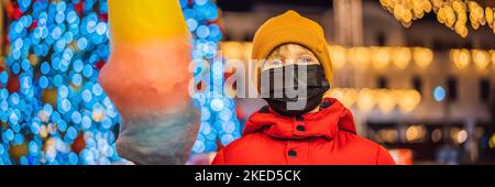 BANNER, LANGFORMATIGER Junge mit Zuckerwatte auf dem weihnachtsmarkt mit Maske während des Coronavirus COVID 19. Glückliches Kind auf dem Weihnachtsmarkt Stockfoto
