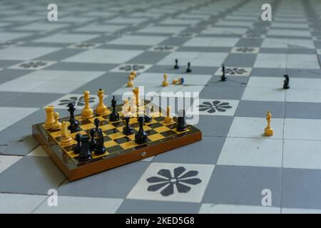 Schachbrett mit verstreuten Figuren steht auf kariertem Boden. Hochwertige Fotos Stockfoto
