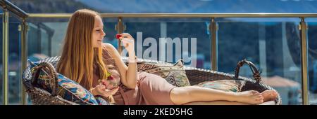 Portrait einer wunderschönen Frau in einem schönen Kleid auf einer Terrasse sitzen und essen Erdbeer-BANNER, LANG FORMAT Stockfoto