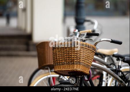 Fahrradkörbe aus Korbgeflecht aus nächster Nähe. Eine Reihe von Leihfahrrädern, die auf einer Stadtstraße geparkt sind. Stockfoto