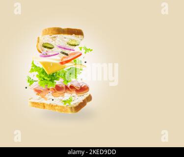 Auf einem hellbeigen Hintergrund ein Sandwich in einem gefrorenen Flug. Fleischstücke, Käse und frisches Gemüse auf Brotscheiben. Minimalismus. Vitamine, Prot Stockfoto