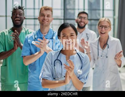 Professionelle multinationale Ärzte applaudieren vor der Kamera. Diagnosediskussion Stockfoto