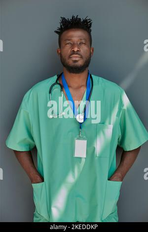 Porträt eines jungen afroamerikanischen Arztes vor grauem Hintergrund Stockfoto