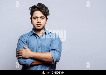 Ein selbstbewusster junger indischer Geschäftsmann in einem formellen Hemd, das mit gekreuzten Armen steht Stockfoto