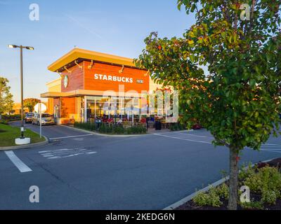 New Hartford, New York - 10. Okt 2022: Weitblick auf das Äußere des Starbuck Building während der Goldenen Stunde mit Fahrzeugen, die durchfahren. Stockfoto
