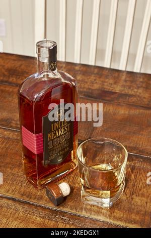 Onkel, das nächste, oberste Regal Tennessee Bourbon Whisky Flasche neben einem Glas Bourbon, ordentlich oder ohne Eis auf einem Tisch. Stockfoto