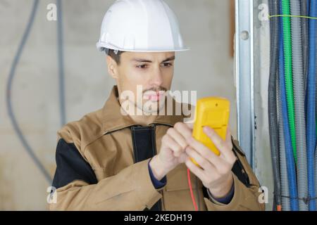 Junger Elektriker bei der Arbeit mit Tester Messung Hochspannung Stockfoto