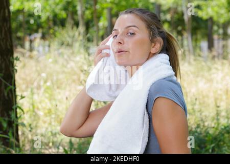 Frau abwischen Braue nach dem Training im Freien Stockfoto