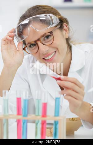 Lächelnder Chemiker mit Schutzbrille und Mantel im Labor Stockfoto