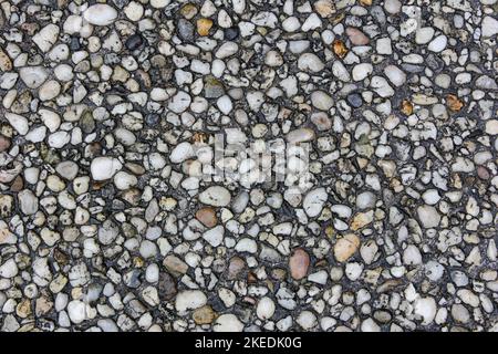 Kleine Kieselsteine in Beton eingebettet – eine Oberflächenstruktur Stockfoto
