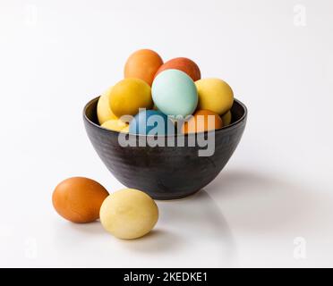 Eine Nahaufnahme von bunt bemalten Ostereiern in einer weißen Keramikschale mit zwei außen Stockfoto