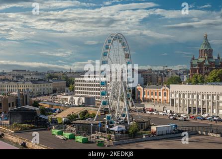 Helsinki, Finnland - 20. Juli 2022: Historischer Hafen. SkyWheel und Uspenski Kathedrale mit ihren roten Backsteinmauern und grünen Kuppeln im Hintergrund unter blauer Wolkenstein Stockfoto