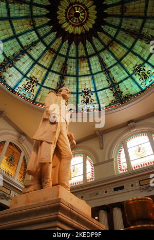 Eine Skulptur von Thomas Jefferson steht unter einem großen Buntglasfenster im Lobbyatrium des Thomas Jefferson Hotels in Richmond Virginia Stockfoto