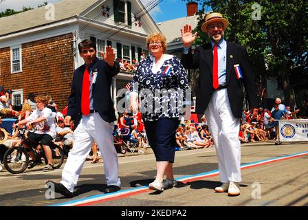 Ein Bürgermeister der Kleinstadt und die Mitarbeiter marschieren und winken am 4. Juli in Bristol Rhode Island, der ältesten Parade zum Unabhängigkeitstag in den USA, vor der Menge Stockfoto