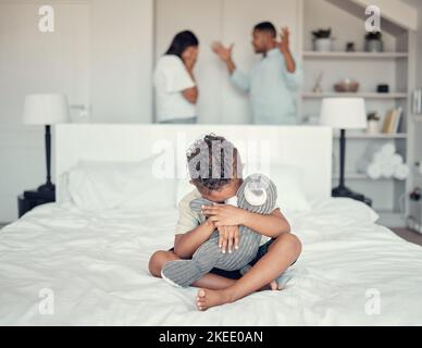 Traurig, kämpfen und Junge auf dem Bett mit Eltern in Konflikt Depression, Angst und Stress in ihrem Familienhaus. Angst, Angst und Kind mit einem Teddybär Stockfoto