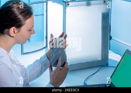 Die junge Frau in einem wissenschaftlichen Labor aus dem Jahr 3D untersucht ein aus Kunststoff gedrucktes Modell Stockfoto