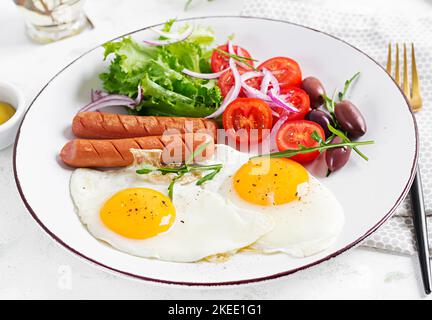 Englisches Frühstück - Spiegeleier, Würstchen, Tomaten und Oliven. Amerikanisches Essen. Stockfoto