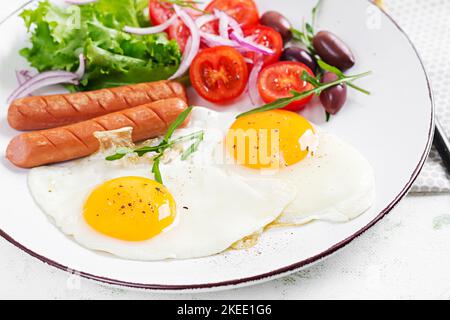 Englisches Frühstück - Spiegeleier, Würstchen, Tomaten und Oliven. Amerikanisches Essen. Stockfoto