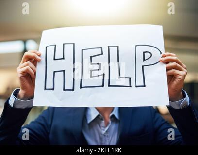 Jeder braucht manchmal ein bisschen Hilfe. Ein Geschäftsmann hält ein Schild und bittet um Hilfe. Stockfoto