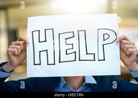 Jeder braucht ein bisschen Hilfe. Ein Geschäftsmann hält ein Schild und bittet um Hilfe. Stockfoto