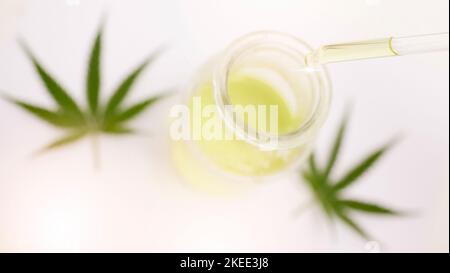 Cannabis, Unkraut und cbd-Öl in einem Glas für Depressionen, Stress und Angst mit legalen Marihuanablättern oder Blumen auf einem Tisch. Dreippig, 420 ODER entspannend Stockfoto