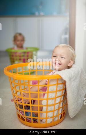 Es war so bequem, dass wir hier nur einen Schlummer machen könnten. Portrait von zwei jungen Mädchen, die in Wäschekörben sitzen. Stockfoto