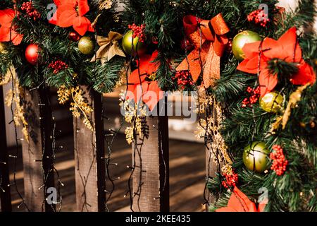 Weihnachtsschmuck und Christbaumzweige am Zaun auf der Straße Stockfoto