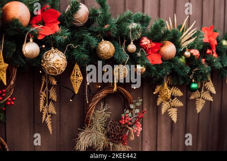 Weihnachtsschmuck und Christbaumzweige am Zaun auf der Straße Stockfoto