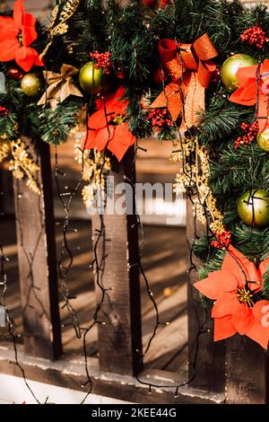 Weihnachtsschmuck und Christbaumzweige am Zaun auf der Straße Stockfoto